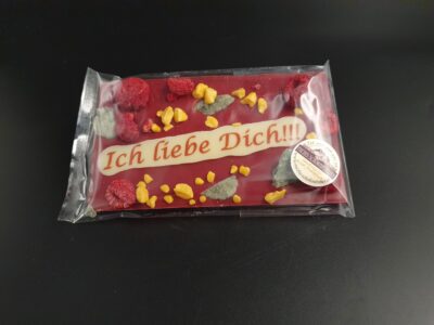 Valentinstafel aus Himbeer-Fruchtkuvertüre mit Spruch "Ich liebe dich" auf weißem Schokoladen-Aufleger