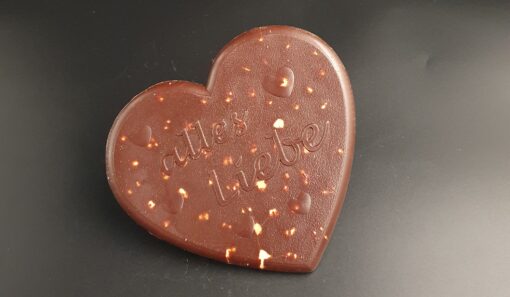 Herz aus Zartbitter-Schokolade mit ganzen Haselnüssen und Schriftzug "alles Liebe"