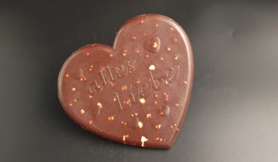 Herz aus Zartbitter-Schokolade mit ganzen Haselnüssen und Schriftzug "alles Liebe"