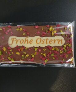 Mini Ostertafel aus Vollmilch-Schokolade mit kristallisierten Rosen, gehackten Pistazien und Aufschrift "Frohe Ostern" (verpackt)