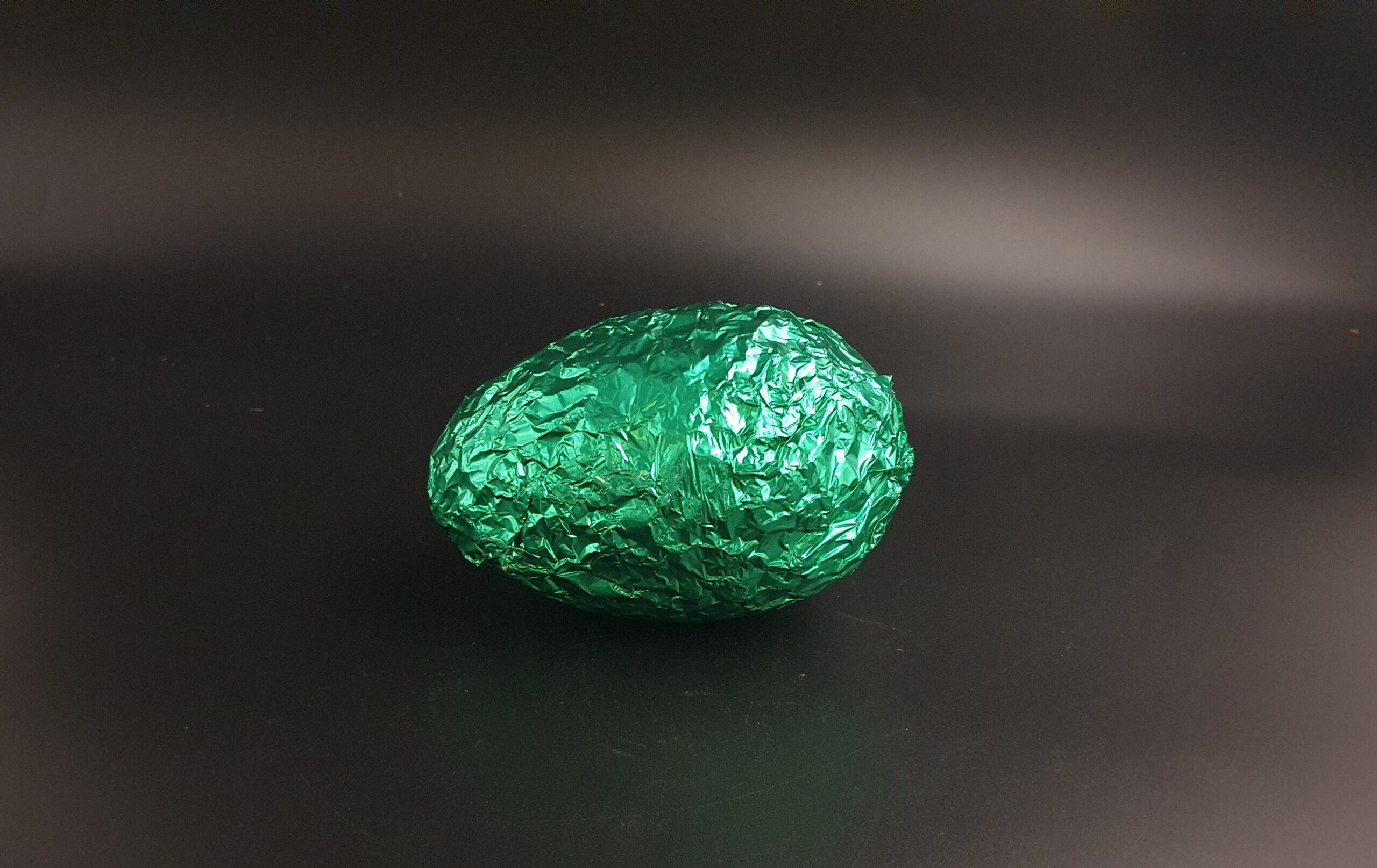 Puffreis-Ei mit Vollmilch-Schokolade, in grün-glänzender Folie verpackt